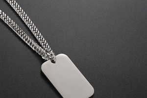 Macro view of polished stainless steel military dog tag pendant with curb chain detail