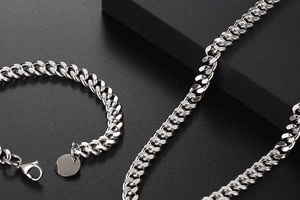 Gros plan d'un bracelet et collier à maille gourmette en acier poli avec fermoir mousqueton