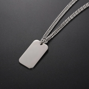 Polished stainless steel dog tag necklace with curb chain on a textured dark background