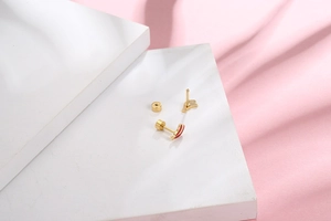 Detailed view of mini golden animal silhouette stud earrings with red accents on steps
