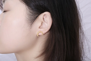 Vue rapprochée d'une boucle d'oreille demi-lune minimaliste en acier titane doré