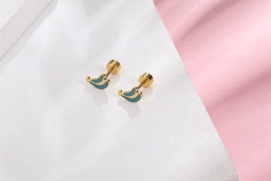 Detail view of gold stud earrings with teal enamel leaves on a white marble background