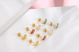 Detail view of colorful rainbow striped screw back stud earrings on marble background