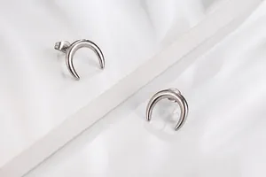 Détail de boucles d'oreilles croissants de lune argentées sur un support blanc moderne