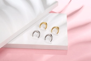 Détail de boucles d'oreilles croissant en argent et or sur des marches blanches épurées