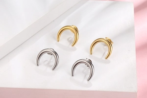 Vue macro de boucles d'oreilles croissants de lune en acier doré et argenté mat