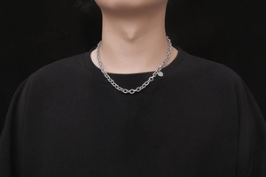 Detailed view of silver stainless steel chain necklace with oval links and round tag