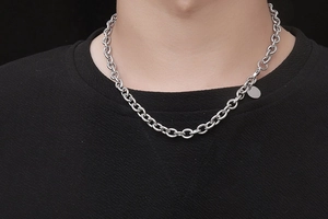 Close-up of a chunky silver stainless steel chain necklace with round links and a small tag