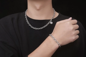 Detail shot of silver stainless steel chain necklace and matching bracelet on a model