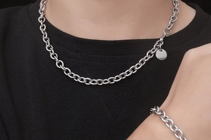 Detail of silver steel thick link necklace with a polished round charm on model
