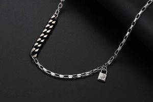 Dettaglio della collana a catena mista con pendente a lucchetto inciso a stella