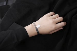 Detail eines zweifarbigen Gliederarmbands mit gravierbarem Anhänger am Handgelenk