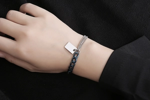 Detail eines Gliederkettenarmbands mit silbernem rechteckigem Anhänger und Bicolor-Design