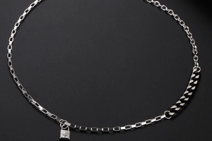 Dettaglio della collana a catena multipla con pendente a lucchetto inciso con stella