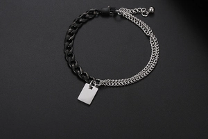Details eines zweifarbigen Panzerketten-Armbands mit silbernem Anhänger und Karabinerverschluss