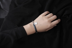 Dettaglio bracciale bicolore blu e argento con ciondolo rettangolare sul polso