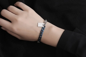 Dettaglio del bracciale bicolore argento e blu con piastrina rettangolare sul polso del modello