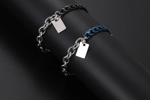 Dettaglio di bracciali a catena bicolore con targhette rettangolari incisibili
