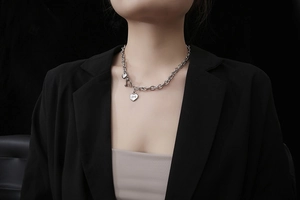 Detail van zilveren stalen ketting met holle hartvormige hanger en LOVE-gravure bij dames