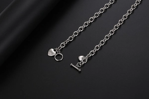 Macro-opname van zilveren hartvormige hanger met LOVE-gravure en T-sluiting aan de ketting