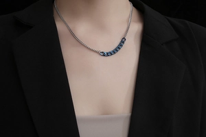 Detail der minimalistischen asymmetrischen silber-blauen Panzerkette auf schwarzem Anzug