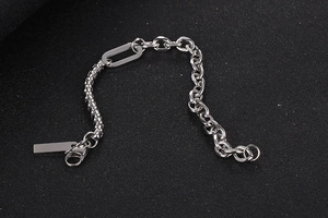 Details des silbernen Gliederketten-Armbands mit rechteckigem Anhänger auf dunklem Grund