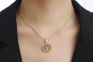 Detail van de levensboom ketting in goud op een zwart jasje voor vrouwen