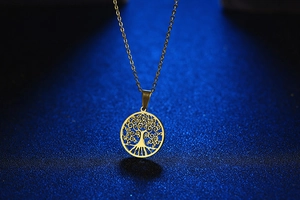 Detail van een gouden levensboom hanger aan een fijne schakelketting met graveringen