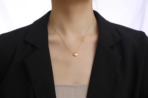 Golden heart lock necklace with key pendant shown on a model wearing a black blazer