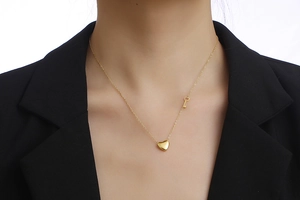 Detailed view of gold heart pendant and mini key charm on a minimalist chain necklace