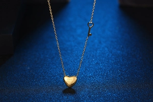 Macro shot of gold heart pendant engraved with Love Forever 520 and small key charm