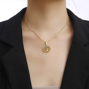 Gouden levensboom ketting op vrouwelijk model die een zwarte blazer draagt