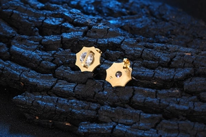 Dettaglio macro di orecchini a stella in acciaio al titanio con zircone e placcatura