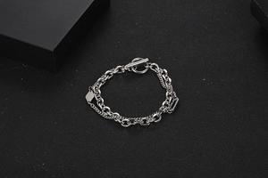 Detail eines silbernen doppellagigen Kettenarmbands mit OT-Verschluss und quadratischem Anhänger