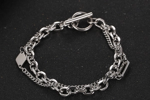 Makroaufnahme von doppellagigem Silberkettenarmband mit OT-Knebelverschluss und Anhängern