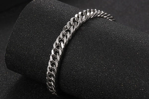Macro view of polished silver Cuban link bracelet on a sleek black display stand