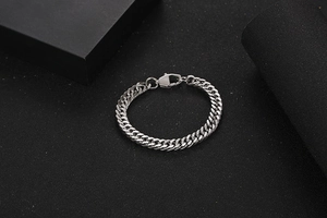Detailed view of polished silver cuban link chain bracelet with lobster claw clasp