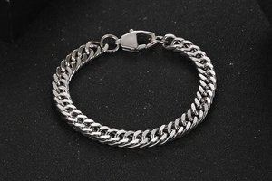 Close-up of silver titanium steel Cuban link bracelet with lobster clasp on black background