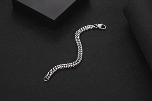 Macro shot of silver Cuban chain bracelet with geometric lobster clasp on black background