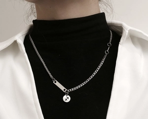 Detalle del collar con colgante Sagitario de acero titanio y cadena asimétrica sobre modelo