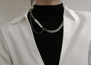 Detalle del collar asimétrico de acero al titanio con perlas y eslabones de cadena cubana