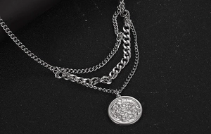 Macro shot of silver layered titanium steel necklaces with a detailed round coin pendant