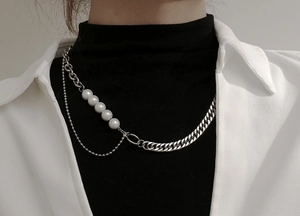 Detalle de collar multicapa de acero de titanio con cadena cubana y perlas blancas