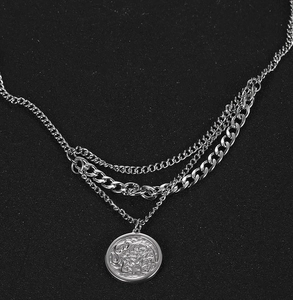 Detailed view of triple-layer silver metal chain necklace with elephant coin pendant