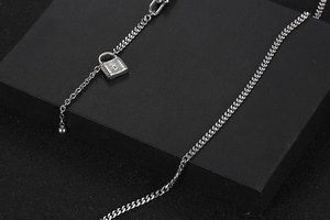 Primer plano de collar de cadena plateada con colgante de candado en fondo negro