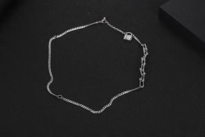 Detalle de collar de cadena plateada asimétrica con un pequeño colgante de candado cuadrado