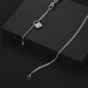 Collar de cadena con hebilla de herradura y colgante de candado sobre caja negra mate