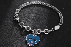 Dettaglio del bracciale a catena punk in acciaio con pendente a teschio in smalto blu
