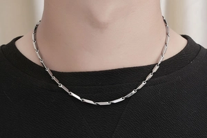 Detail of silver bamboo style link chain necklace for men on black knit sweater