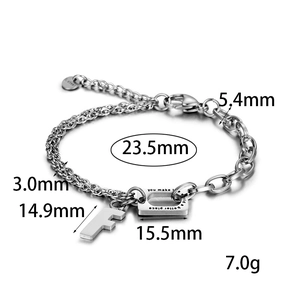 Macro detail of stainless steel bracelet with engraved quote plate and letter F charm